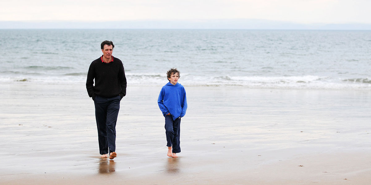 En vuxen man och en pojke gående på en strand