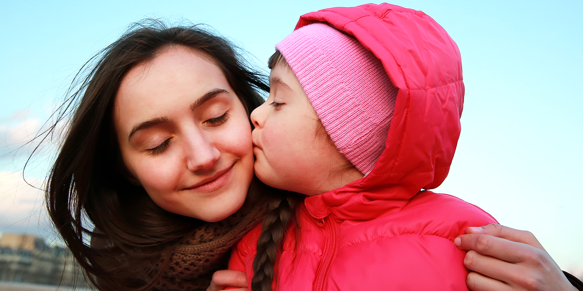 Bild på två barn med en puss på kinden